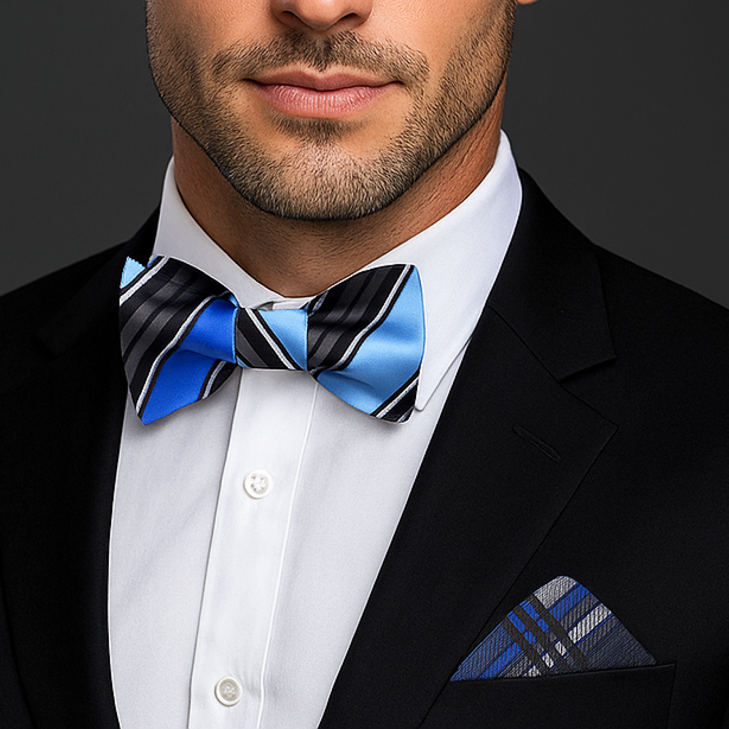 Man wearing a black suit with a blue and black striped bow tie and matching pocket square.