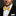 Man wearing a black suit with a white shirt and yellow bow tie with blue stripes on a dark background