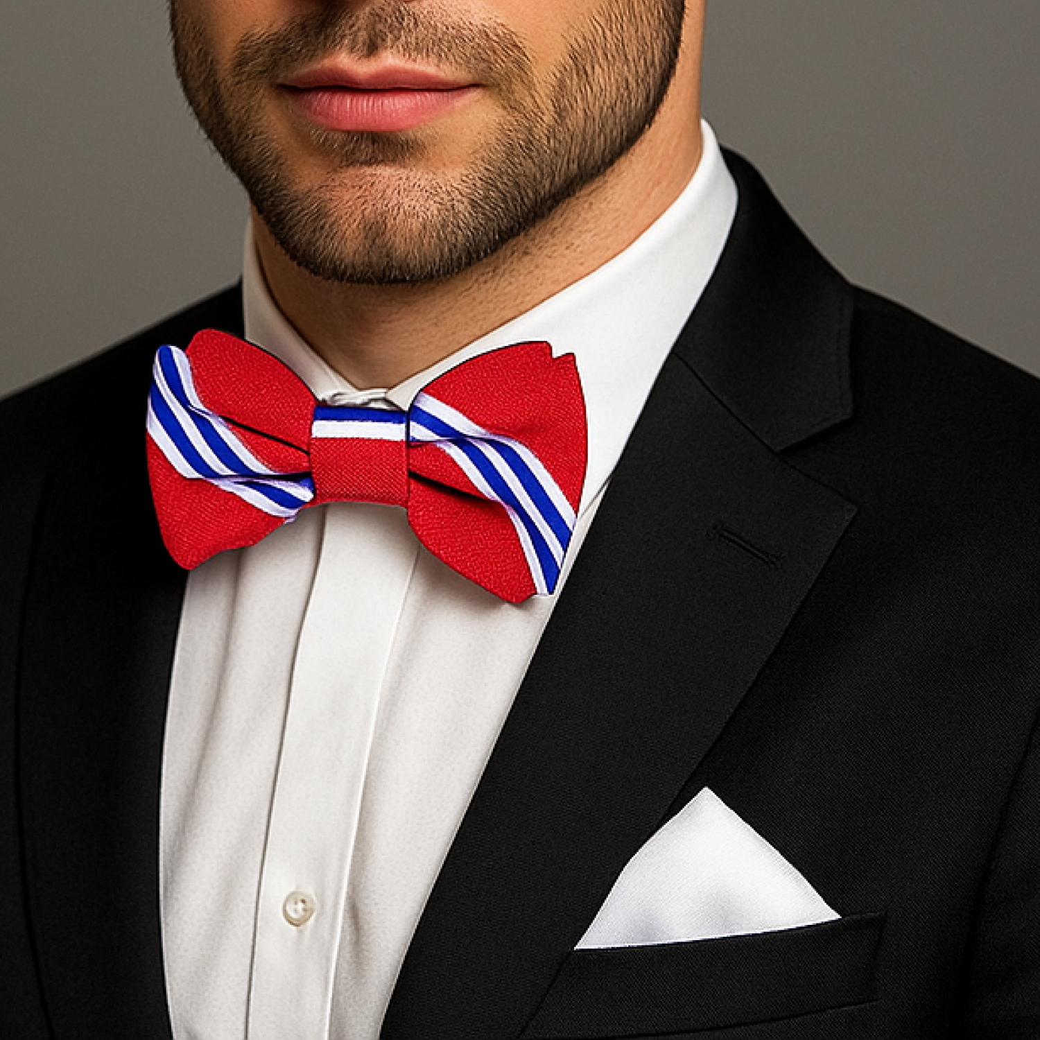 Man wearing a black tuxedo with a red, white, and blue striped bow tie.