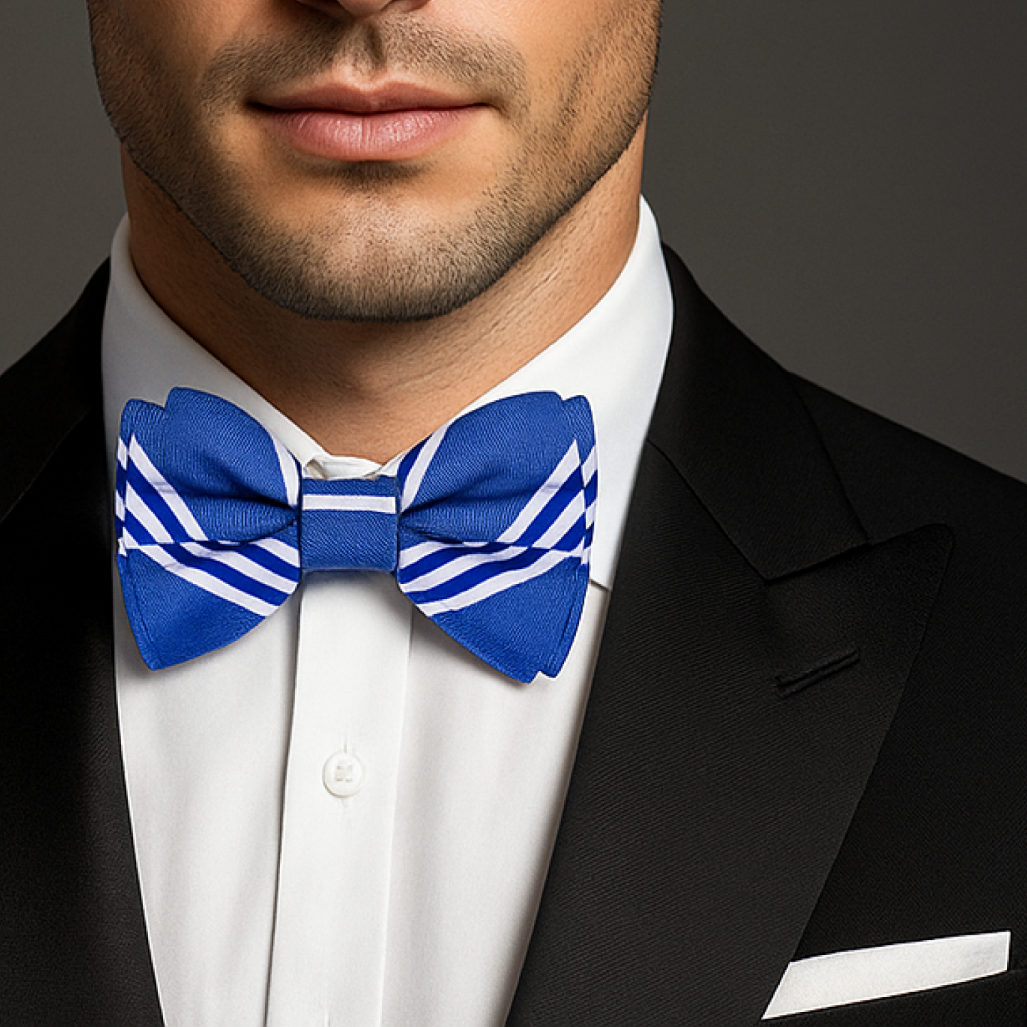 Man wearing a black tuxedo with a blue and white striped bow tie against a dark background