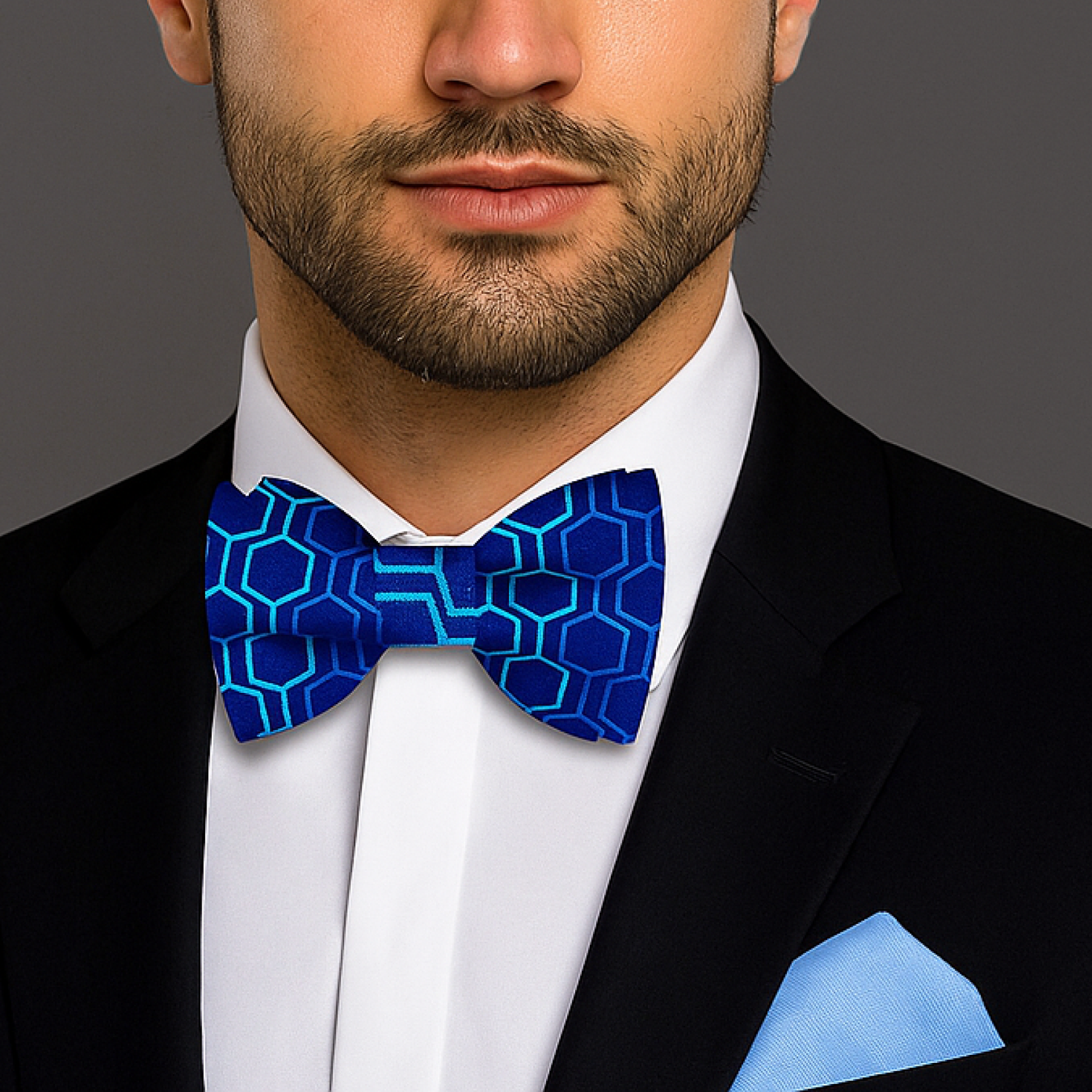 Man wearing a black suit with a blue geometric patterned bow tie and pocket square.