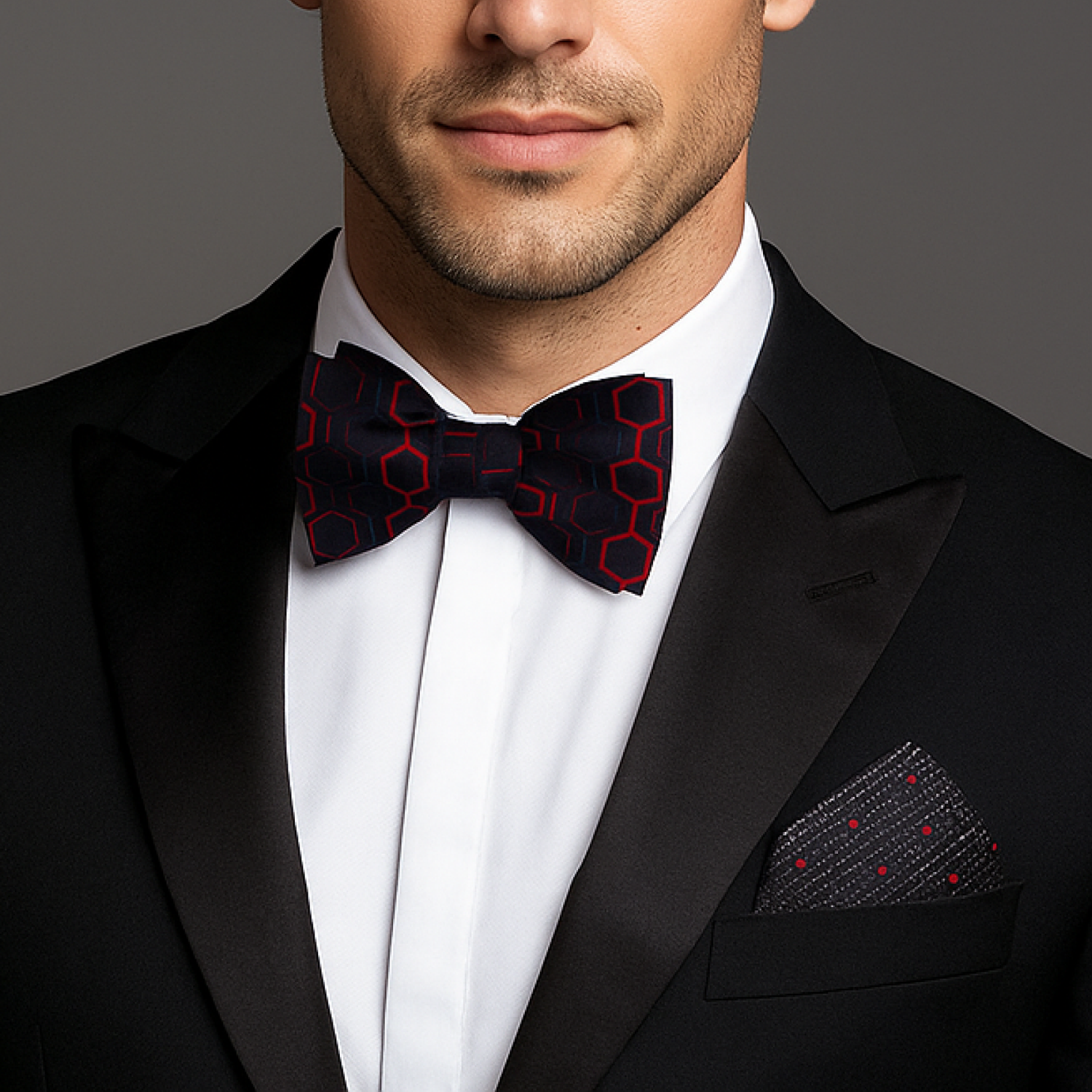Man wearing a black tuxedo with a red geometric bow tie and accenting pocket square.