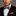 Man wearing a black suit with a grey and coral plaid bow tie and red pocket square on a gray background