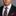 Man wearing a dark suit with a red and black striped tie and matching pocket square on a gray background