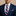 Man wearing a navy suit with a striped tie and pocket square on a beige background