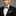Man wearing a black suit with a blue geometric bow tie and pocket square on a gray background
