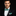 Man wearing a black tuxedo with a green bow tie and pocket square on a black background