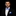 Man wearing a black suit with a blue bow tie and pocket square on a black background