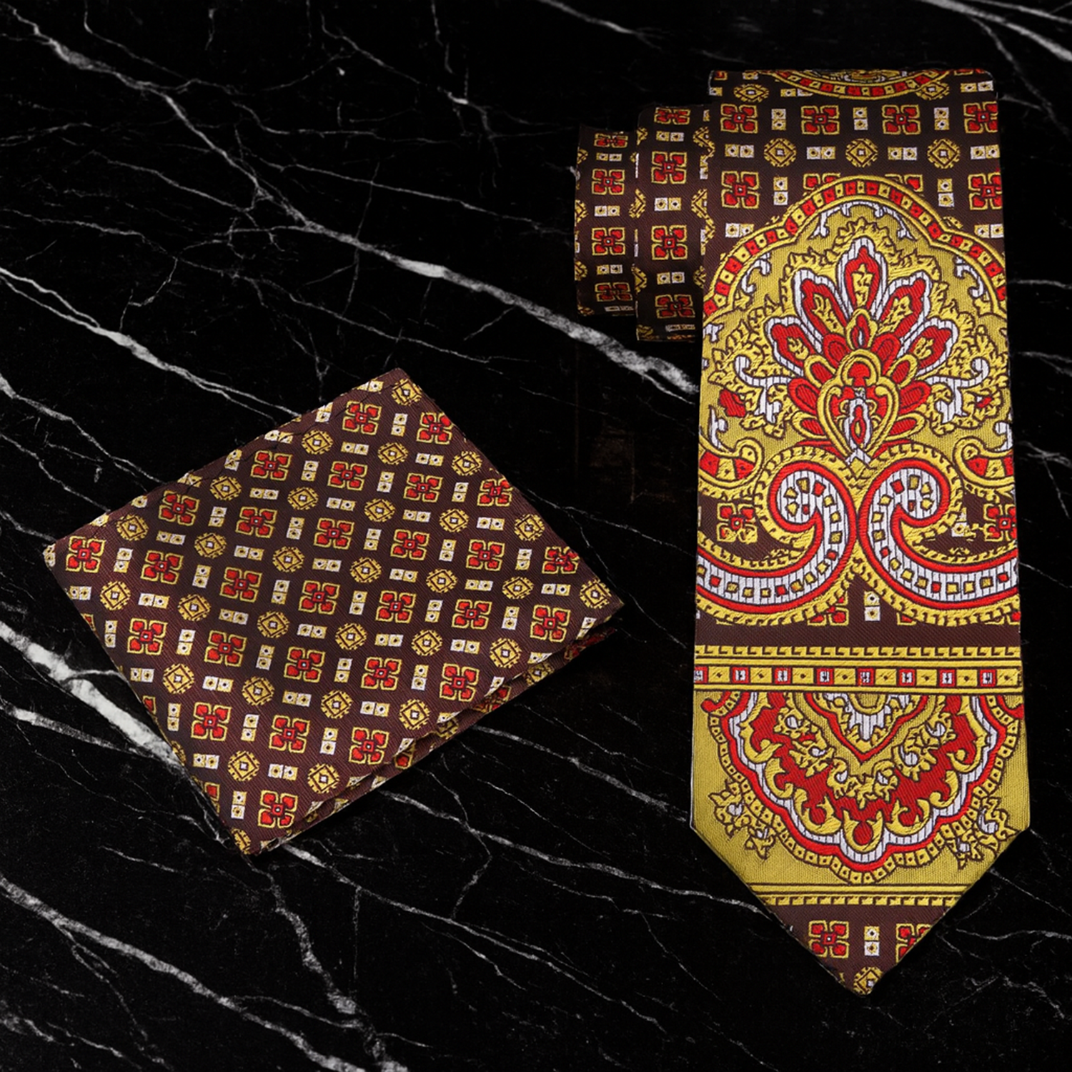 Decorative tie and pocket square set with intricate patterns on a black textured background