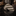 Rolled-up striped tie on a reflective surface with decorative items in the background