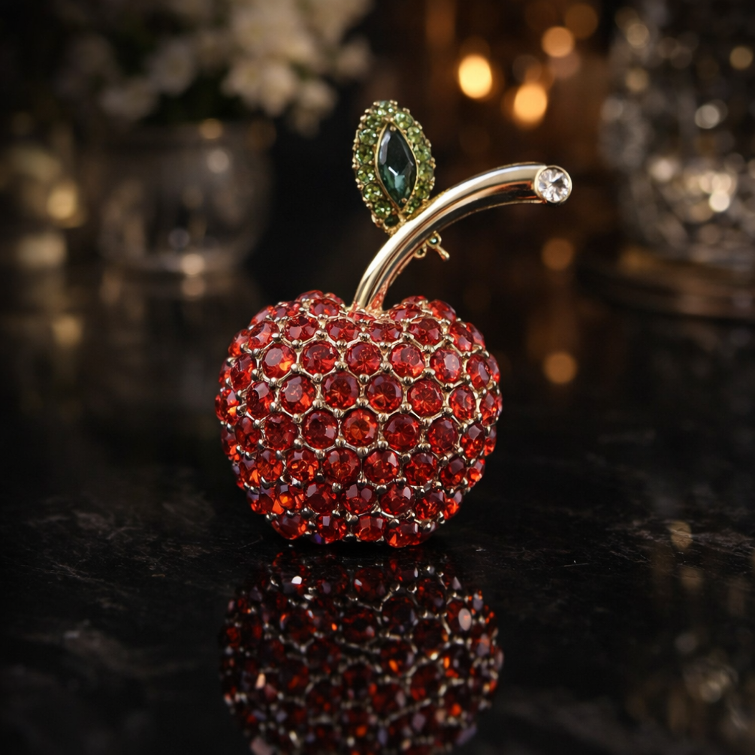 Decorative apple with red gemstones and gold stem on a reflective surface