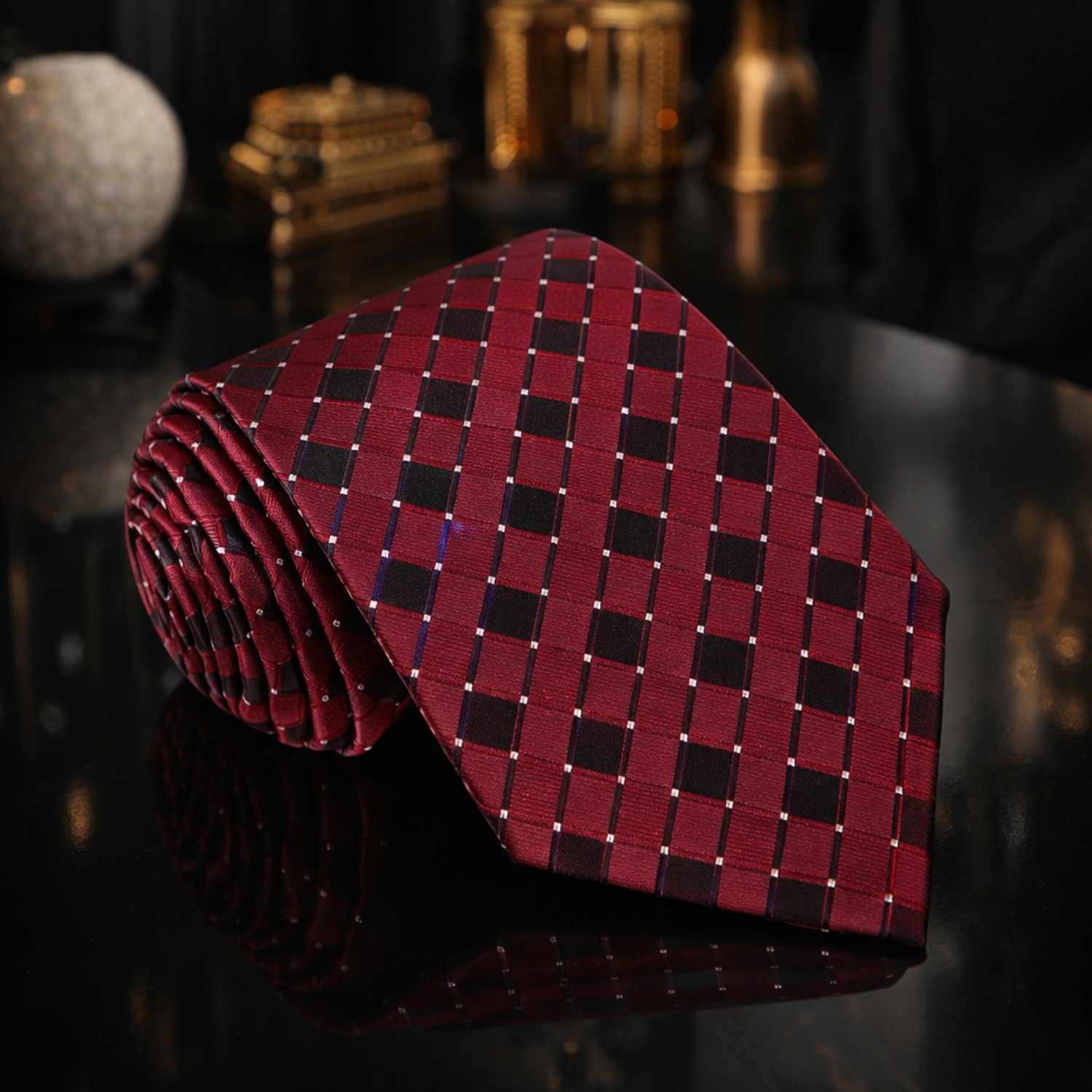 Red and black checkered tie on a dark surface with decorative items in the background