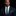 Man wearing a dark suit with a green polka dot thin tie and pocket square against a black background
