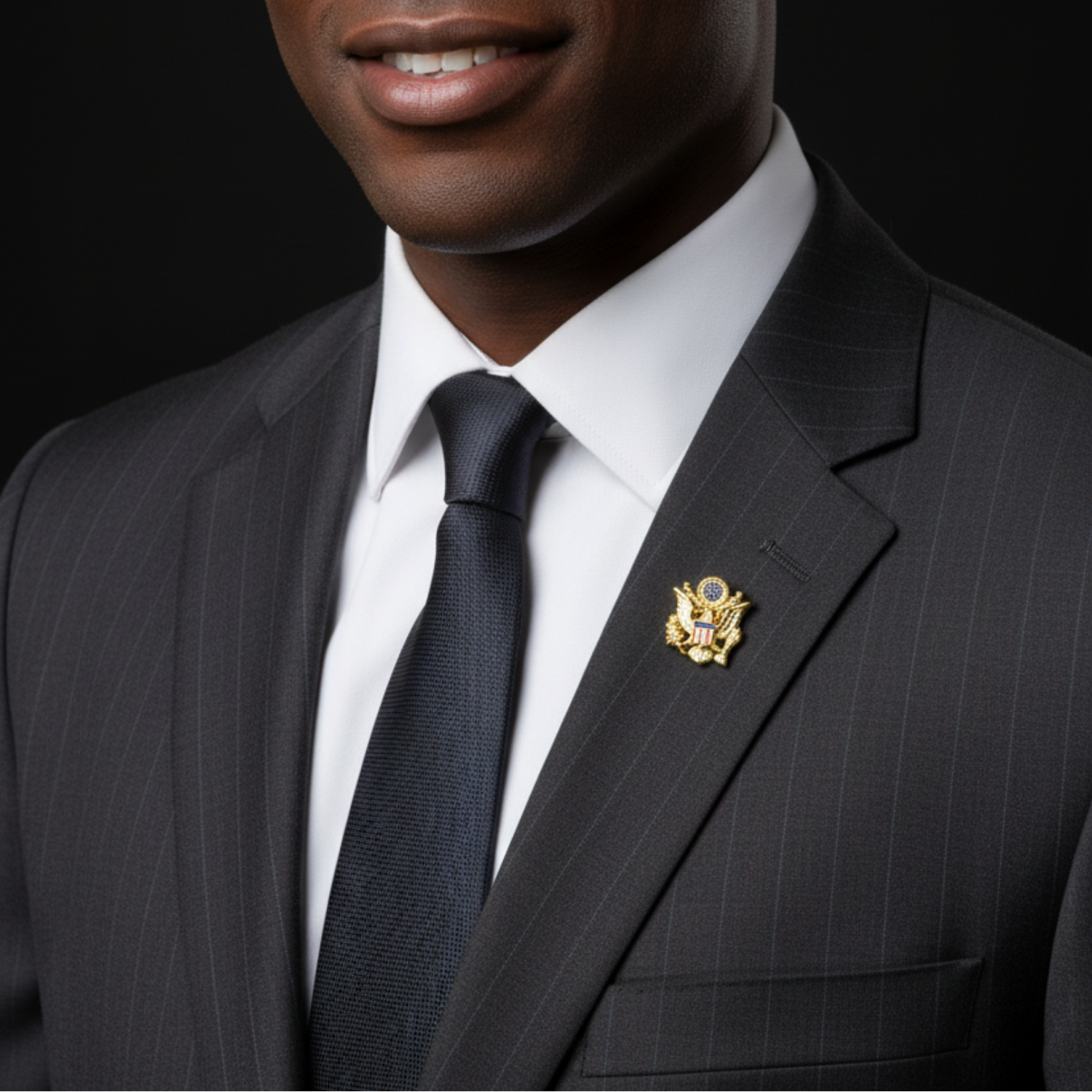 Man wearing a dark pinstripe suit with a white shirt and navy tie, featuring a decorative lapel pin.