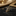 Decorative hummingbird brooch with brown and gold details on a blurred background