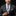 Man wearing a gray suit with a colorful tie and pocket square on a black background