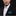 Man wearing a black suit with a white shirt and blue patterned pocket square on a black background