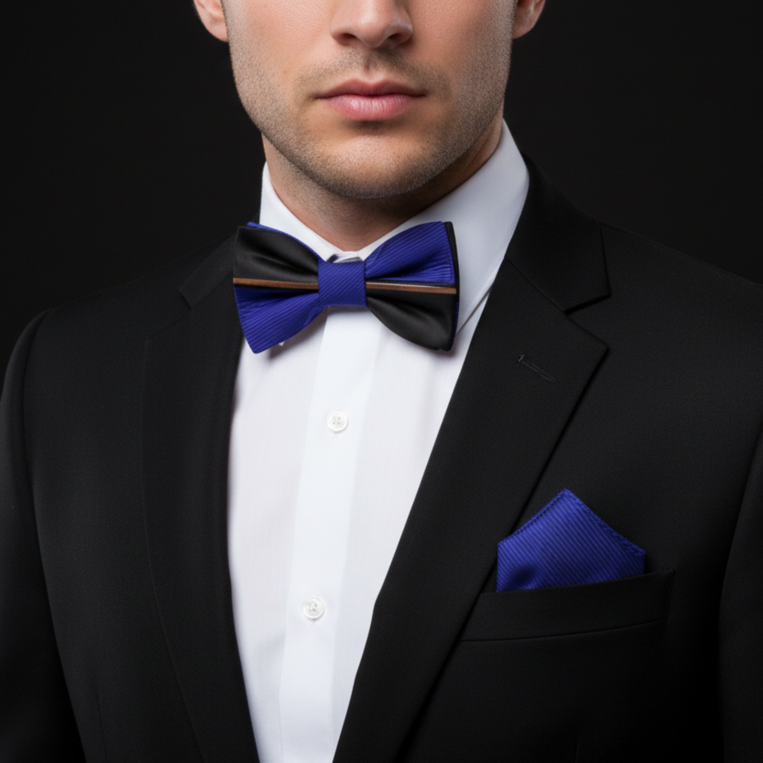 Man wearing a black tuxedo with a blue bow tie and pocket square on a black background