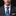 Man wearing a dark suit with a white shirt and a colorful tie against a black background