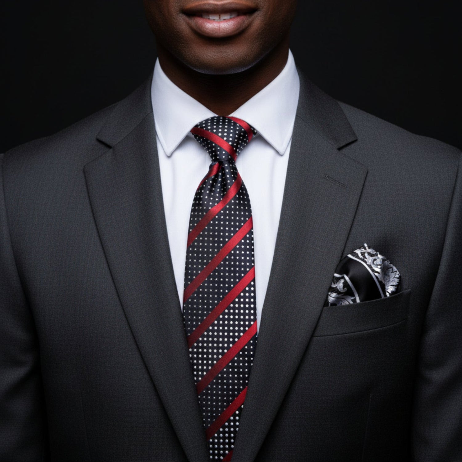 Man wearing a dark suit with a red and black patterned tie against a black background