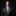 Man wearing a black suit with a green patterned tie on a dark background