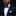 Man wearing a navy suit with an orange pocket square and bow tie against a black background