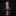 Man in a black suit with a patterned tie against a dark background
