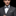 Man wearing a gray suit with a patterned bow tie and pocket square on a black background