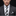 Man wearing a gray suit with a checkered tie and pocket square on a black background