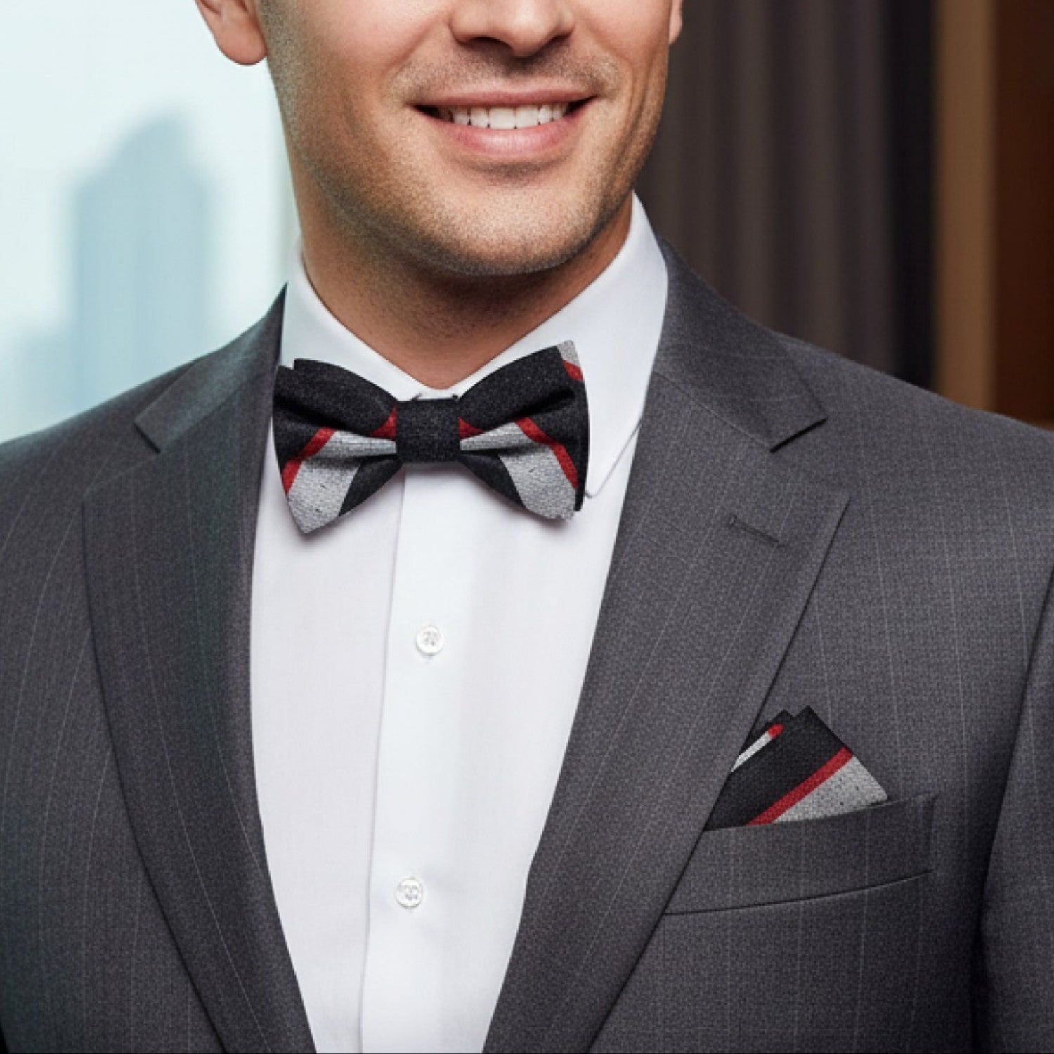 Man wearing a gray suit with a patterned bow tie indoors