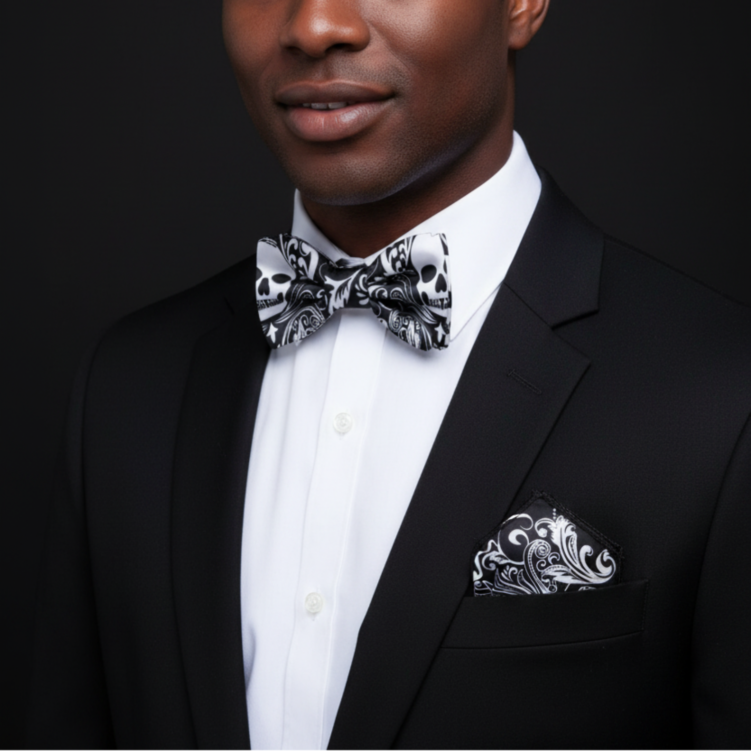 Man wearing a black tuxedo with a white shirt, black bow tie, and matching pocket square against a dark background.