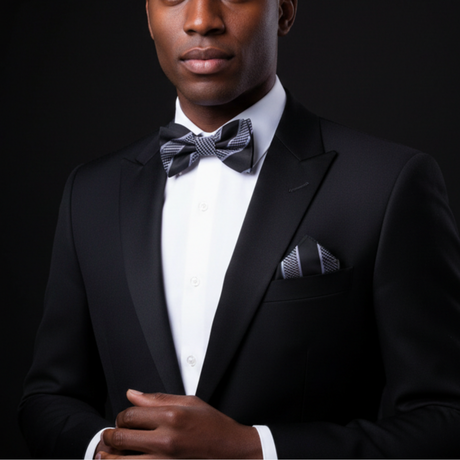 Man wearing a black tuxedo with a bow tie on a black background