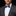 Man wearing a gray suit with a white shirt and blue paisley bow tie on a black background