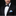 Man wearing a black tuxedo with a polka dot bow tie and blue handkerchief on a black background