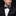 Man wearing a black tuxedo with a patterned bow tie and pocket square against a black background