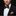 Man wearing a black suit with a patterned bow tie and pocket square on a dark background