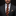 Man wearing a dark suit with a patterned tie and pocket square against a black background