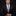 Man wearing a black suit with a patterned tie on a dark background