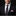 Man wearing a black suit with a patterned tie and colorful pocket square against a black background