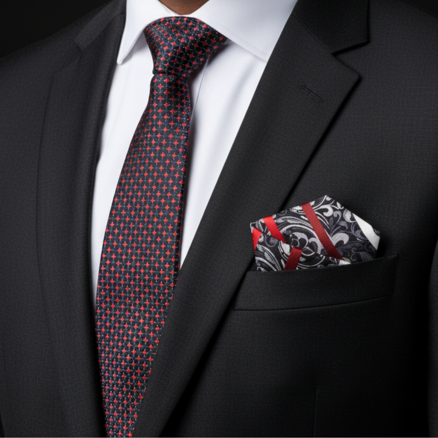 Man wearing a black suit with a red and blue patterned tie and matching pocket square.