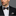 Man wearing a black suit with a patterned bow tie and pocket square on a gray background
