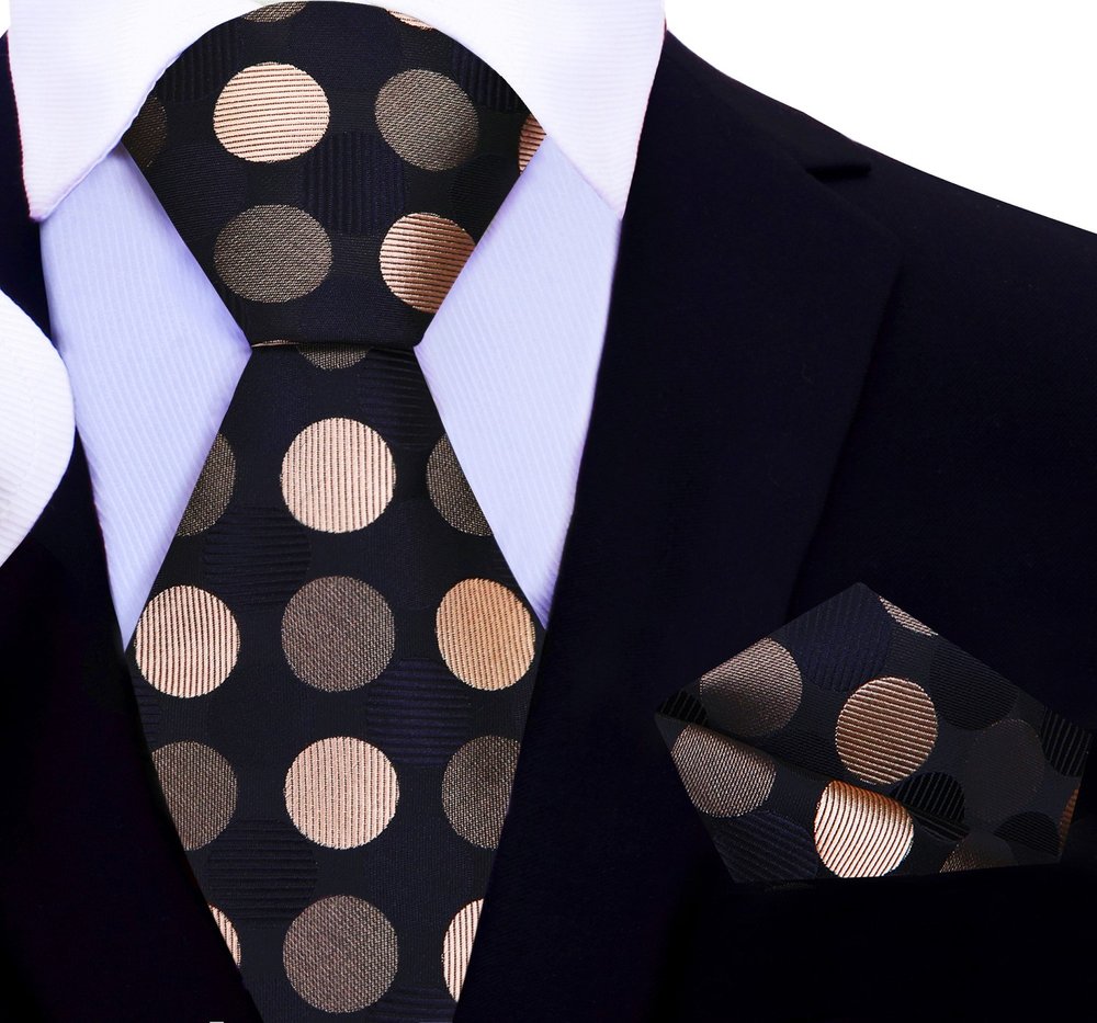 Black tie with gold polka dots worn with a suit and white shirt.