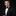 Man wearing a black tuxedo with a red bow tie on a black background