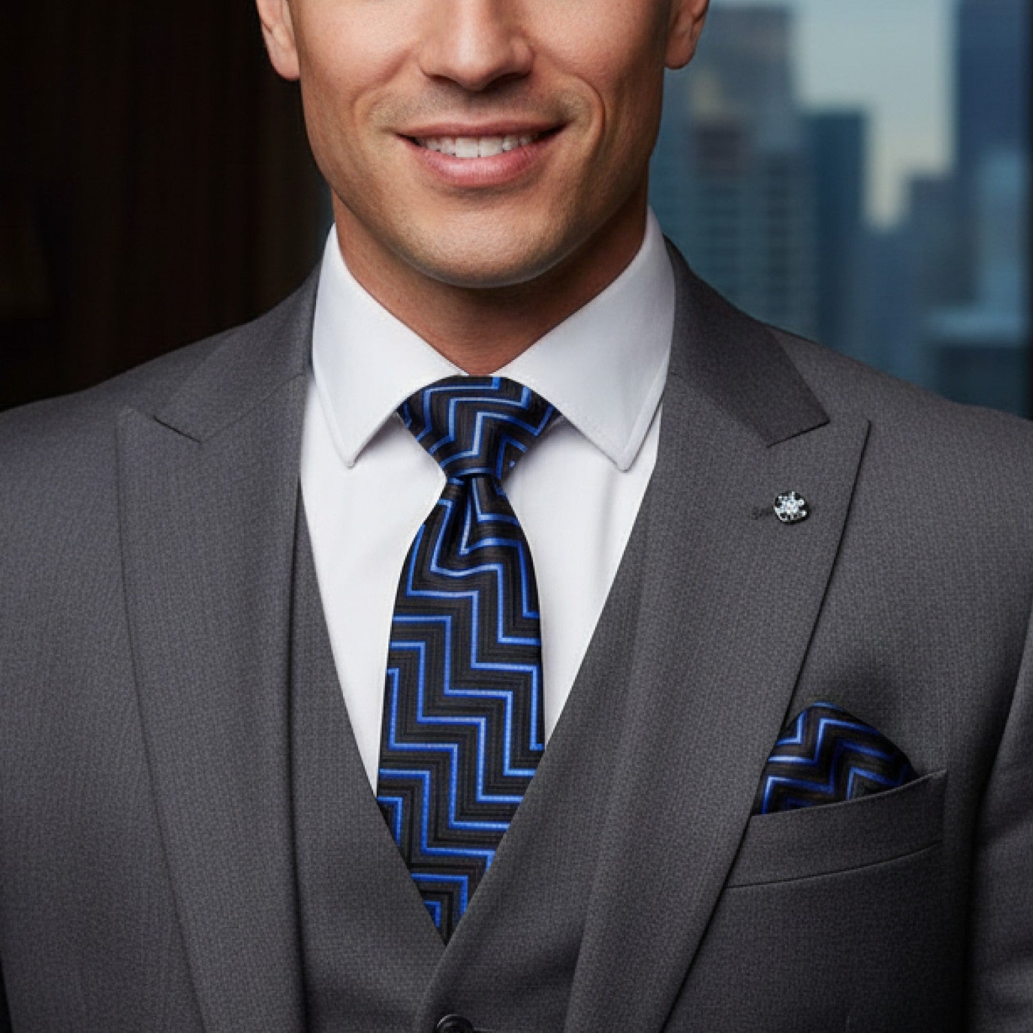 Man wearing a gray suit with a blue and black patterned tie in front of a blurred cityscape.