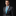 Man wearing a dark suit with a colorful tie and pocket square on a black background