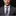 Man wearing a gray suit with a patterned tie and pocket square on a black background