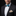 Man wearing a black suit with a colorful bow tie and pocket square on a black background