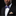Man wearing a black suit with a white shirt and purple bow tie featuring white polka dots on a black background.