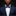 Man wearing a navy suit with a patterned bow tie and pocket square against a dark background