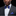 Man wearing a dark suit with a blue bow tie and matching pocket square on a black background